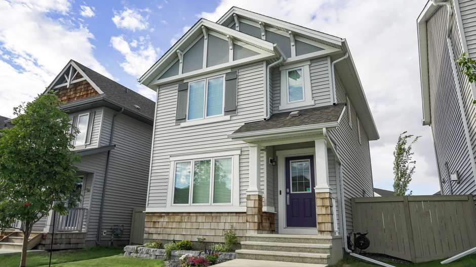 A contemporary single-family home with a front porch under a clear blue sky.